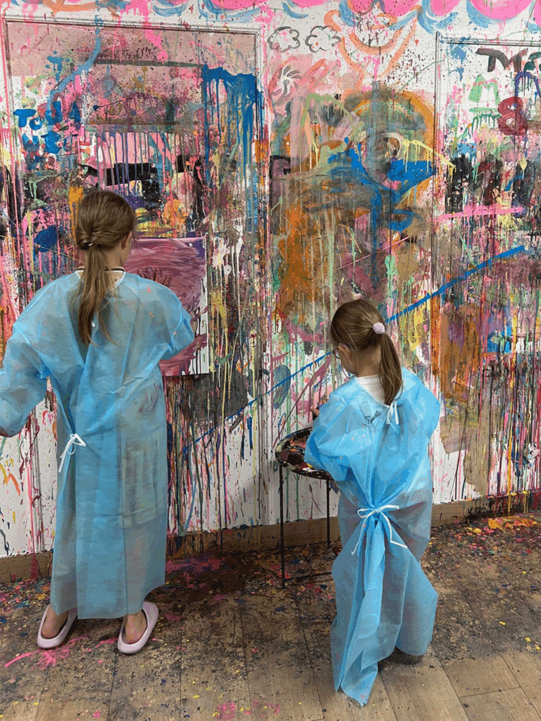 Dzieci malują obraz poprzez chlapanie farbami.