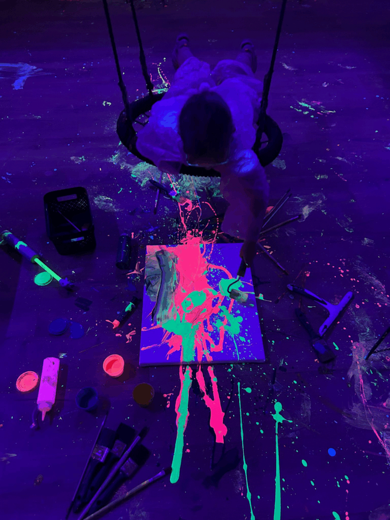 Dziecko maluje na huśtawce farbami FLUO.