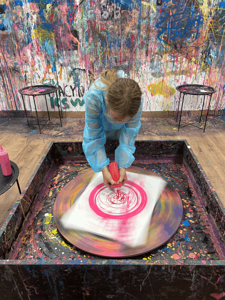 Dziewczynka maluje farbami na kręcącym się kole.