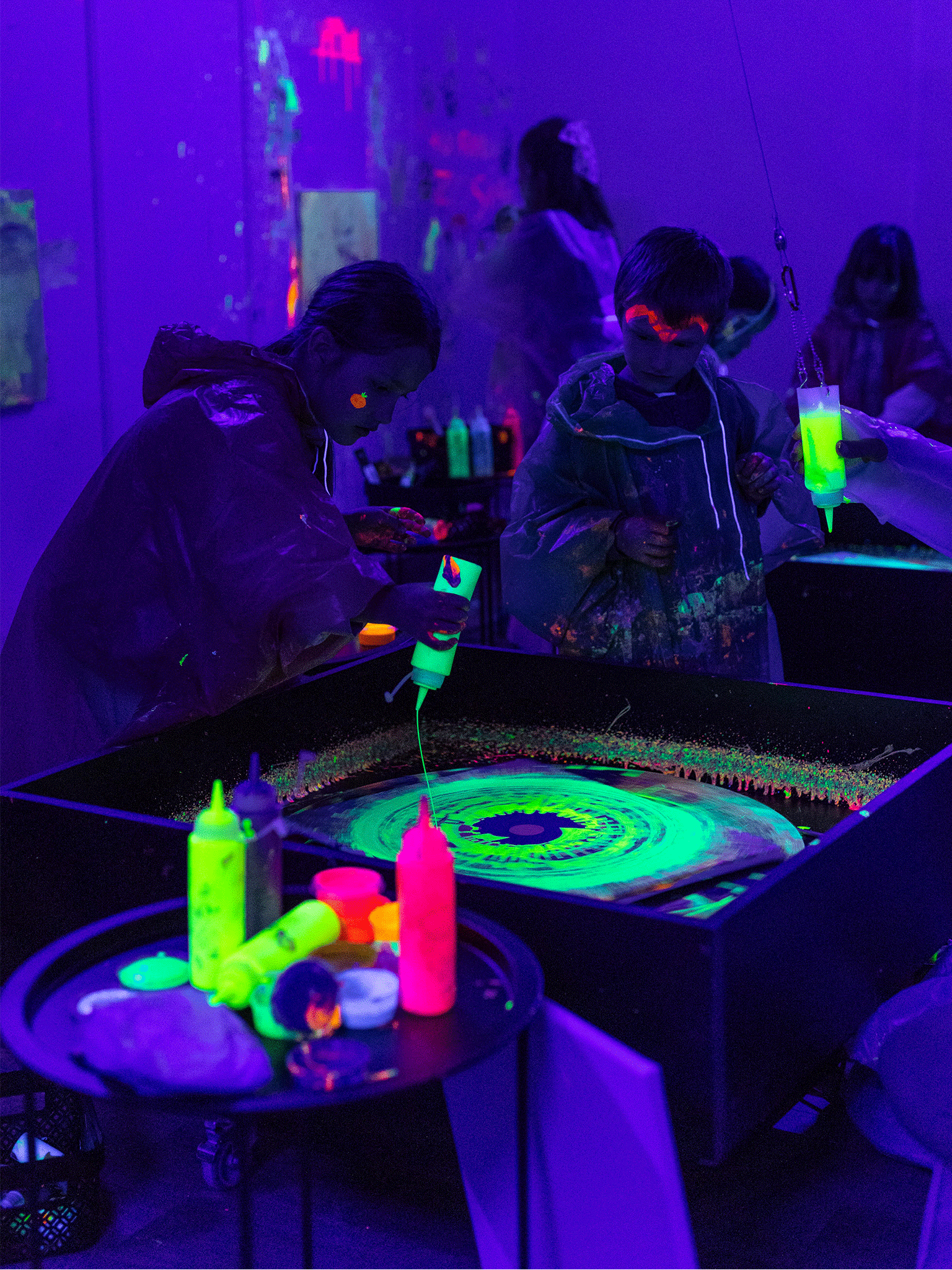 Dzieci malują obrazy na kole w świetle UV.